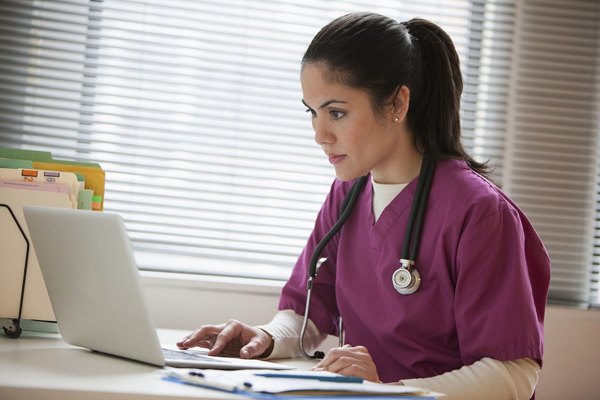 Female provider in scrubs looking at computer